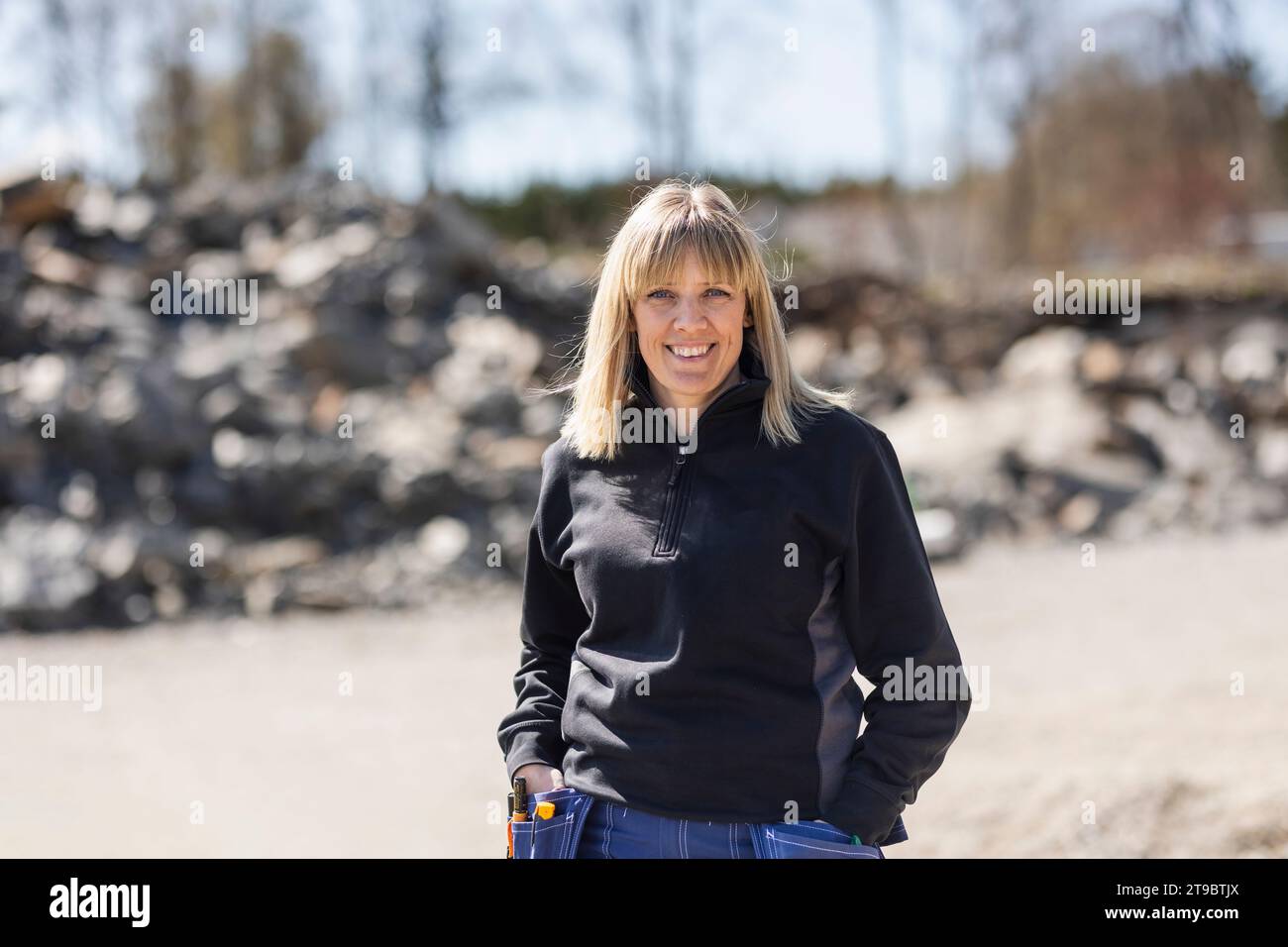 Portrait of smiling female electrician with hands in pockets Stock Photo