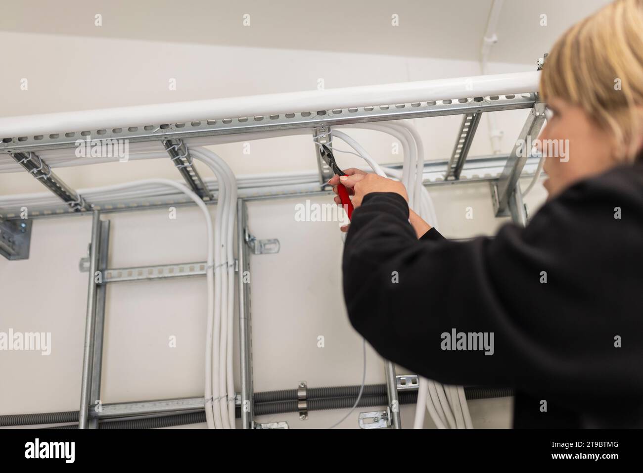 Female technician installing cables in industry Stock Photo