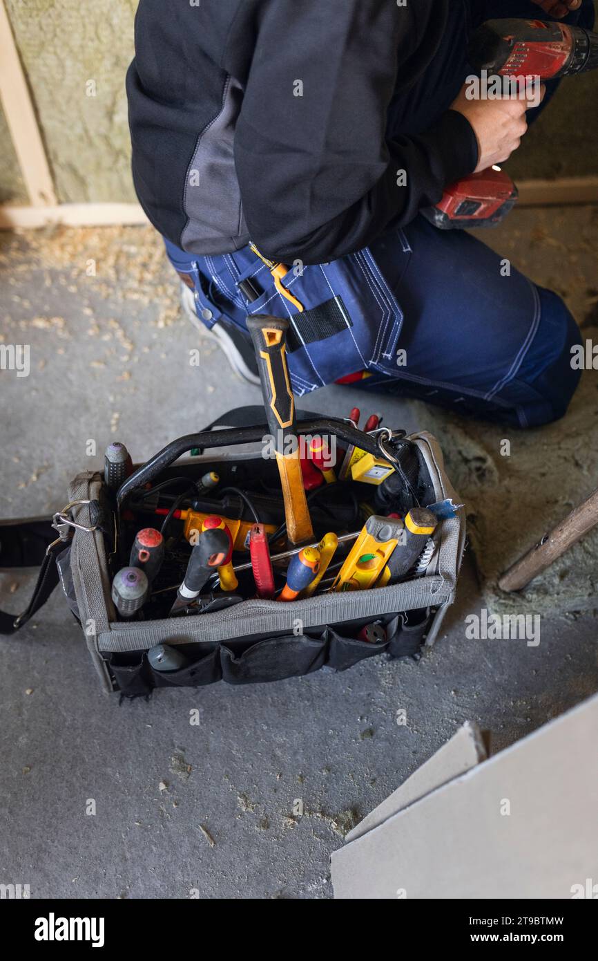 Midsection of female technician with drill machine by tool box Stock Photo
