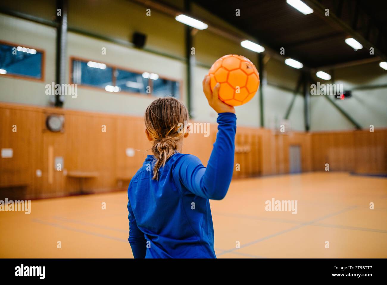Rear view of girl holding handball in sports court Stock Photo