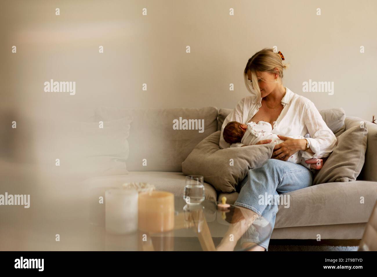 Mother breastfeeding son while sitting on sofa at home Stock Photo