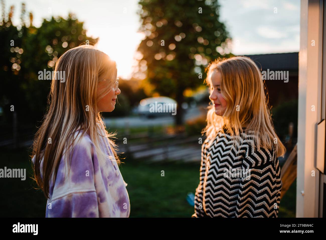 Smiling female friends with blond hair looking at each other Stock Photo