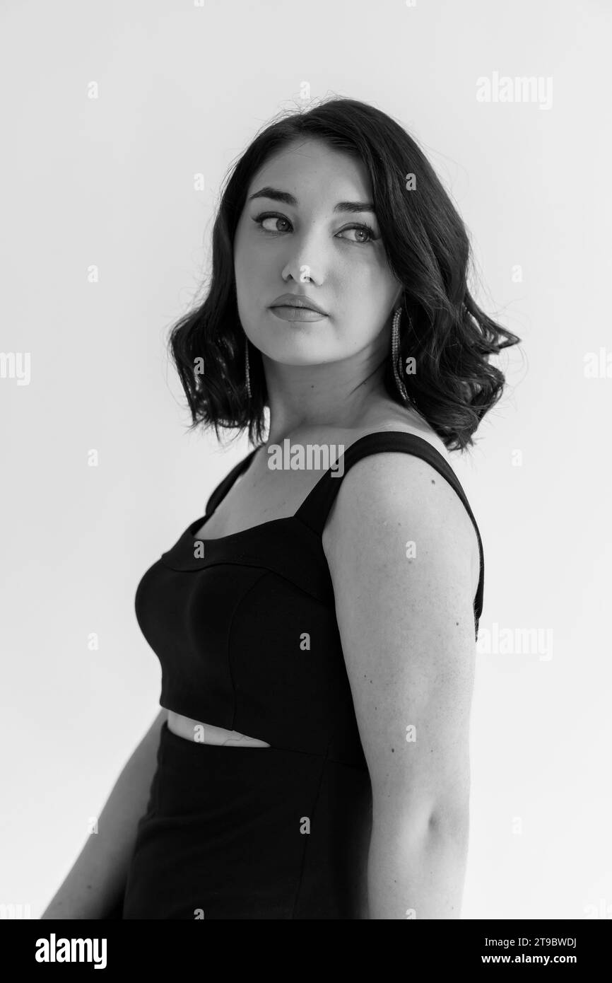 Portrait of a young beautiful girl in a black dress on a gray ...