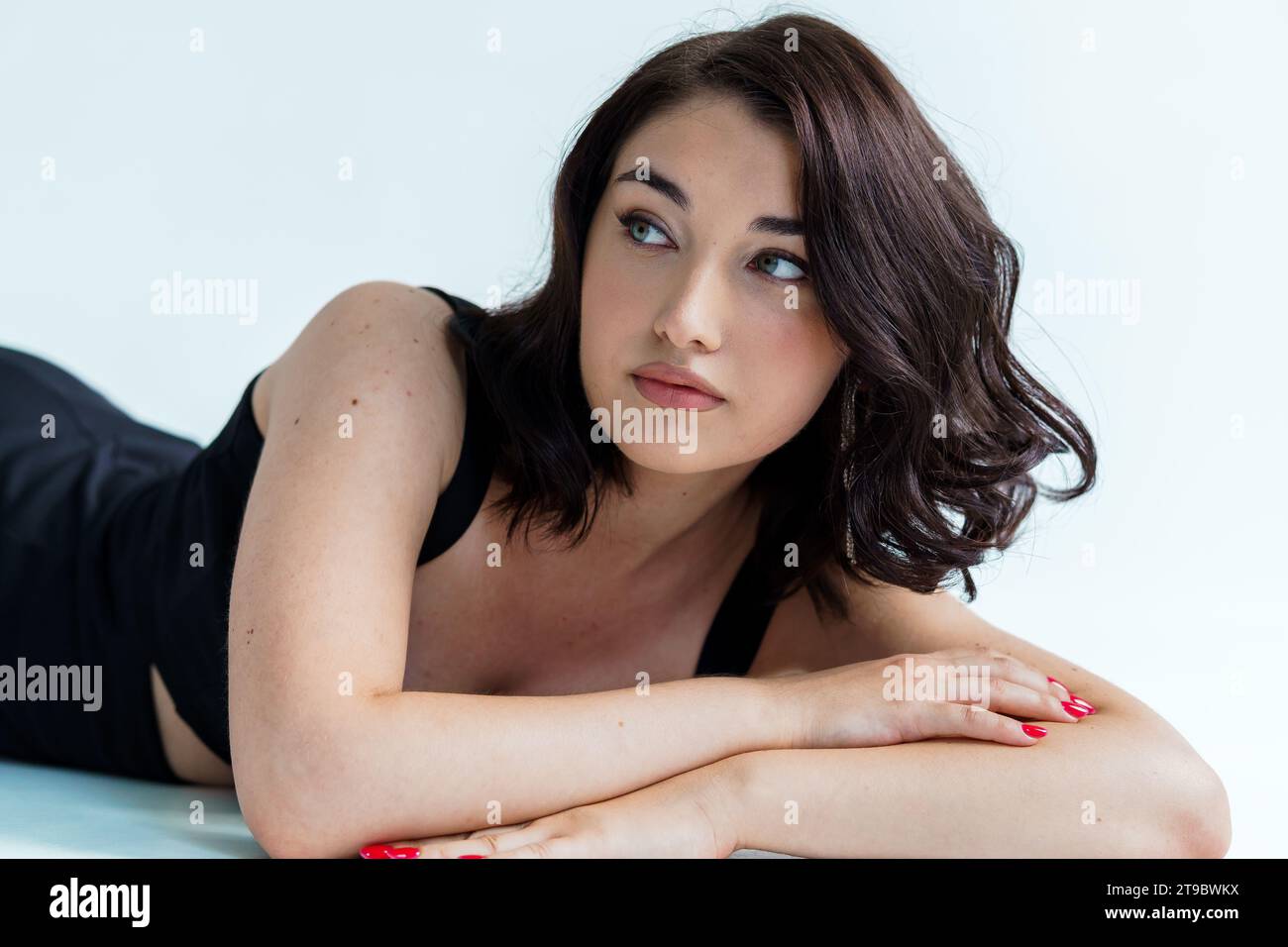 Portrait of a young beautiful girl in a black dress on a gray ...