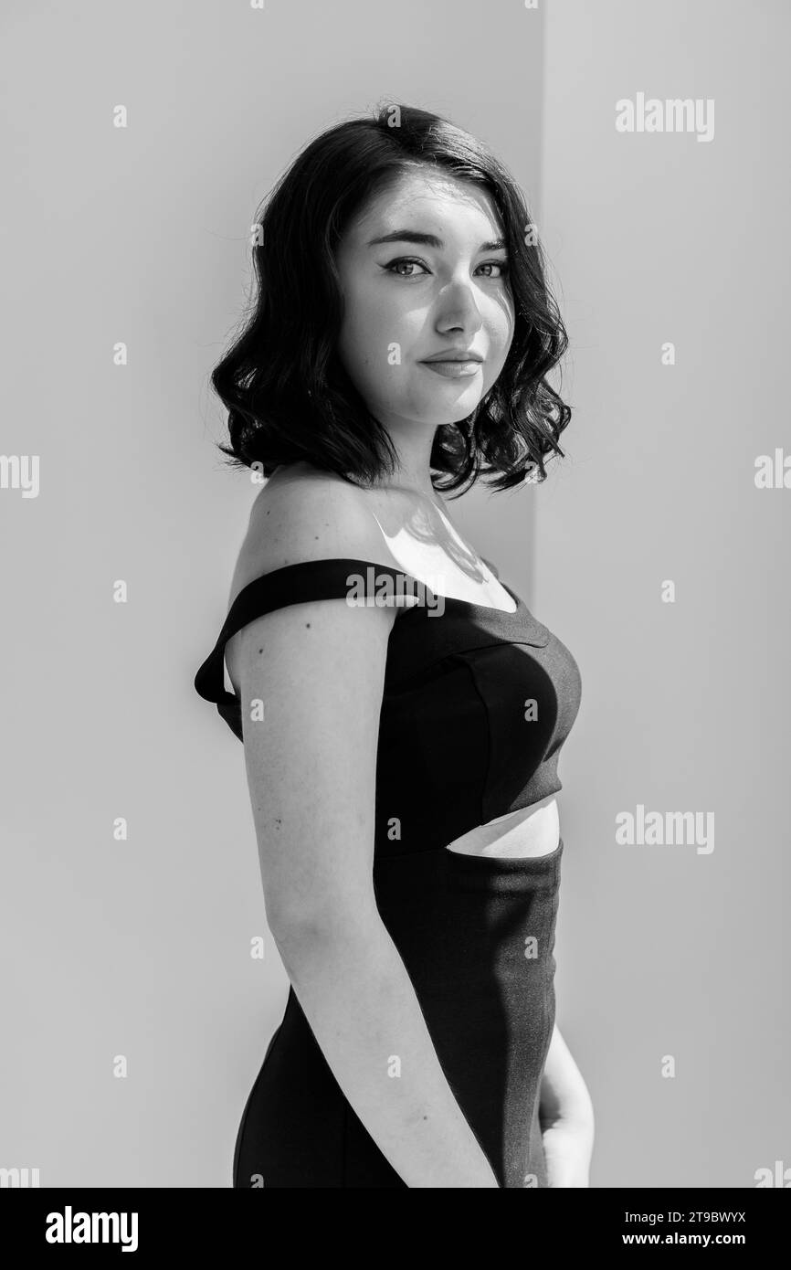 Portrait of a young beautiful girl in a black dress on a gray ...