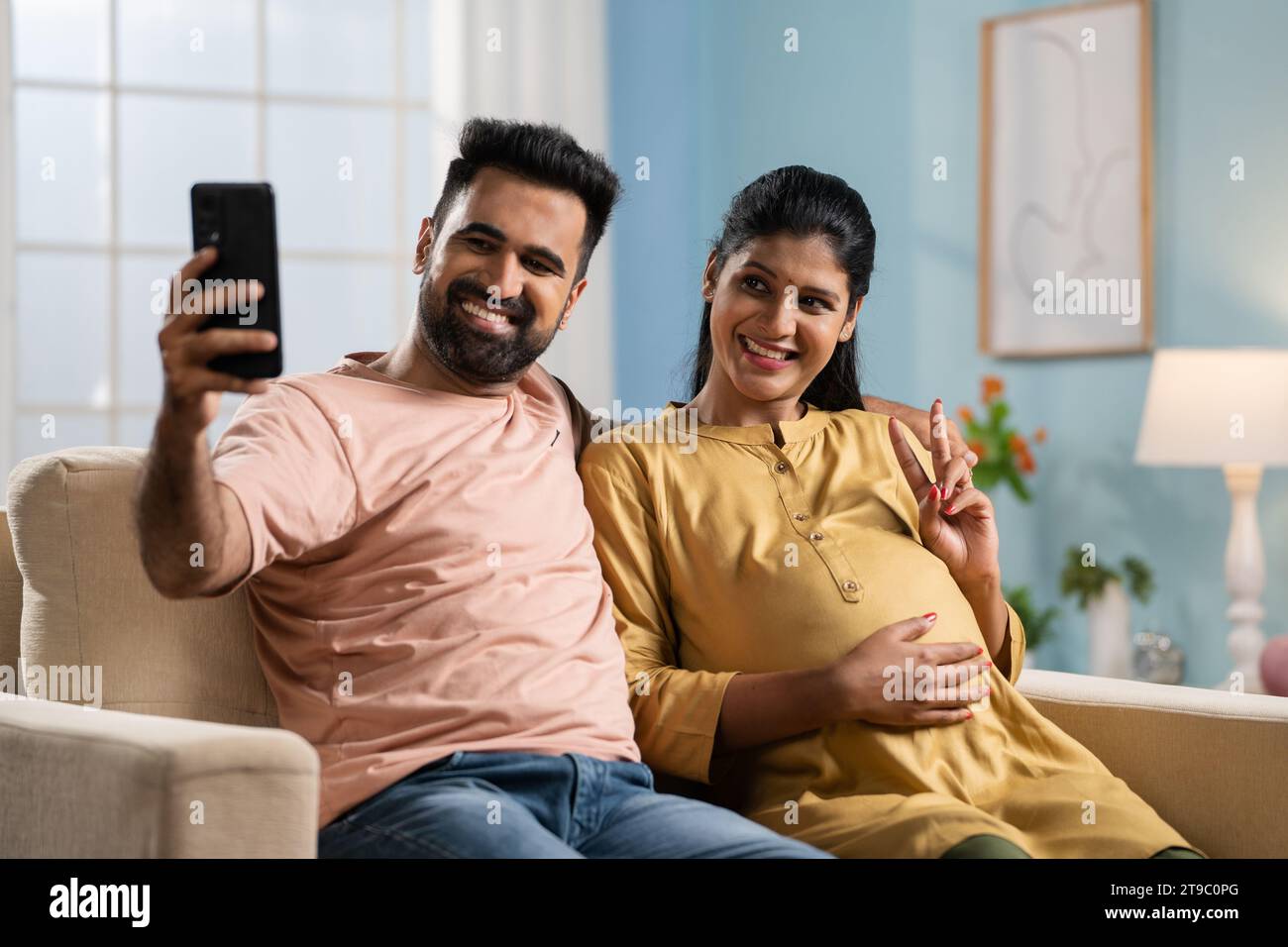 Happy Indian husband with pregnant wife taking selfie on mobile phone - concept of parenthood, family bonding and new beginnings Stock Photo