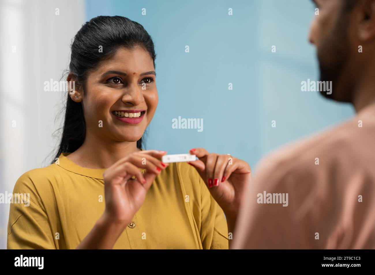 Shoulder shot of excited Indian wife showing positive pregnancy test to husband by hugging at home - concept of Anticipating parenthood, Shared Stock Photo