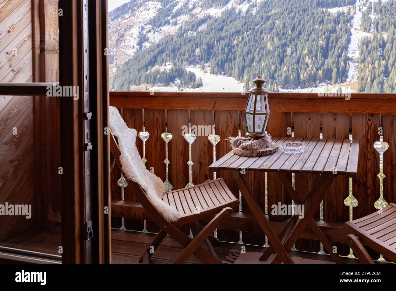 Cozy wooden balcony of the hotel room with folding furniture, mountain view with ski lift, Austria Stock Photo