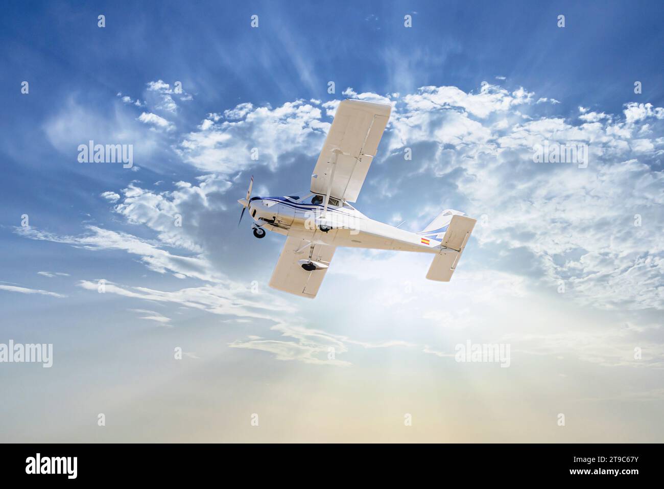 Single engine ultralight plane flying in the blue sky with white clouds Stock Photo