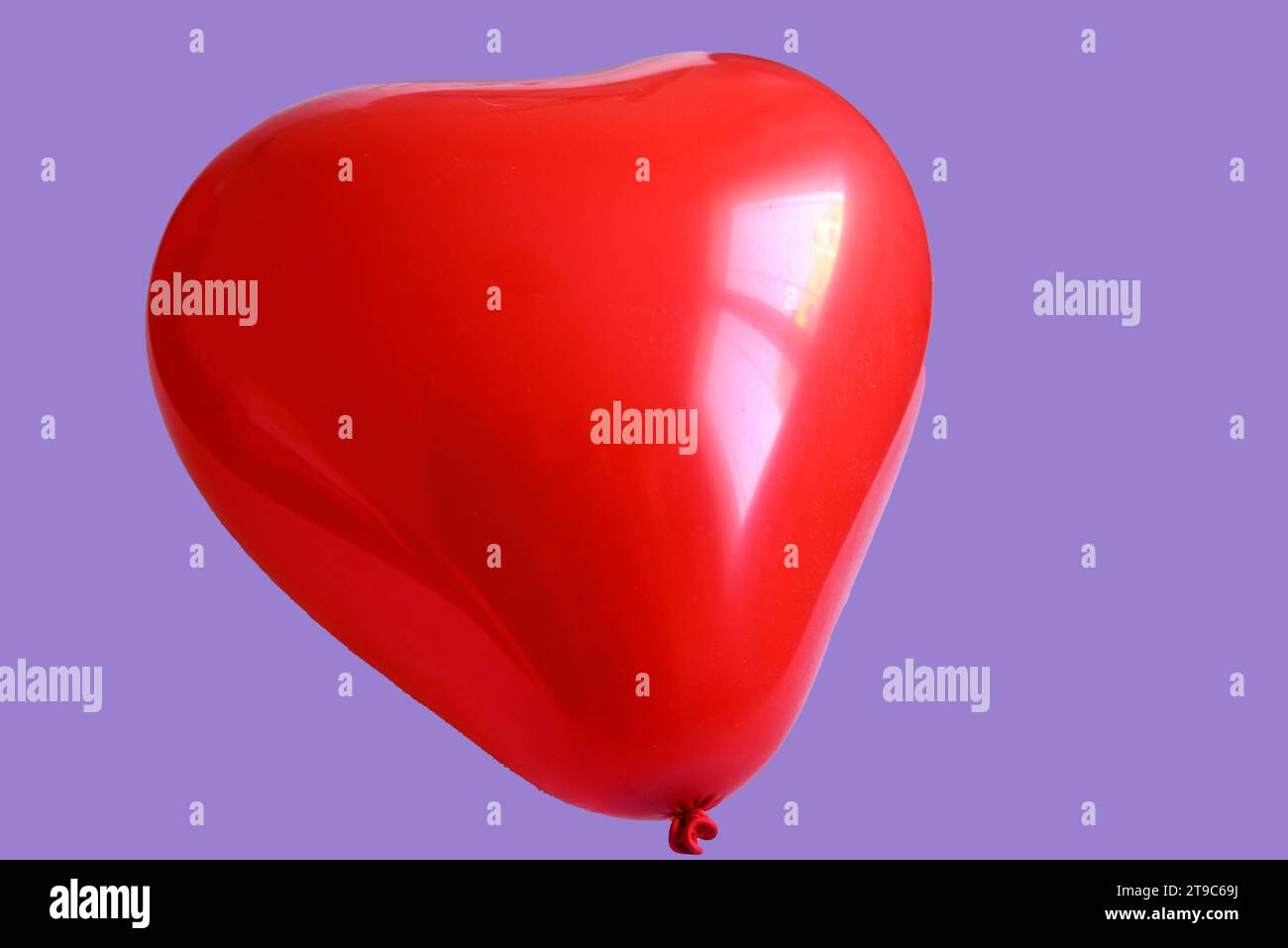 Red heart shaped balloon on violet background Stock Photo
