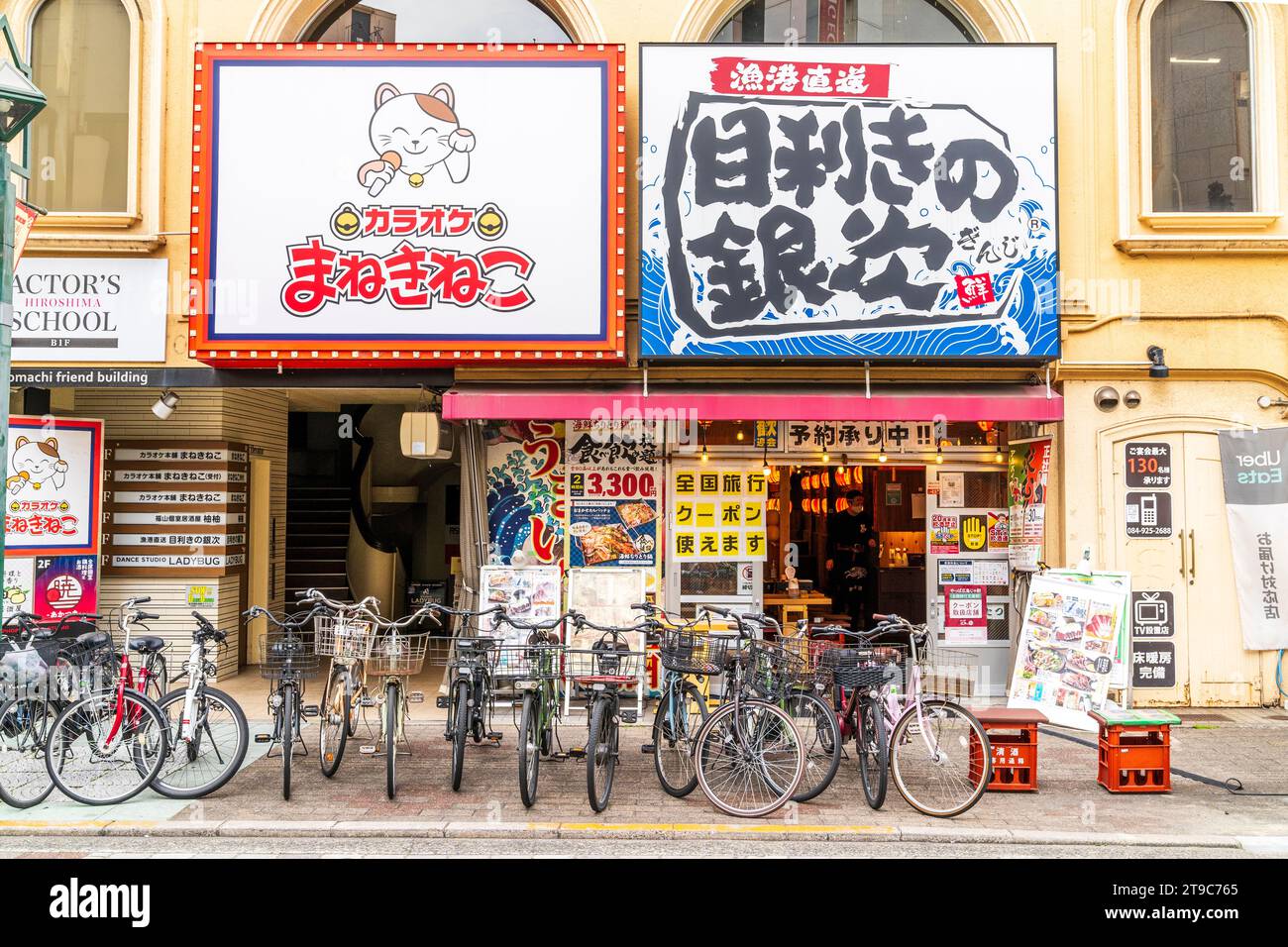 Exterior of building with a ground floor Izakaya restaurant and above a karaoke parlour. Row of bicycles parked outside on pavement. Fukuyama, Japan. Stock Photo