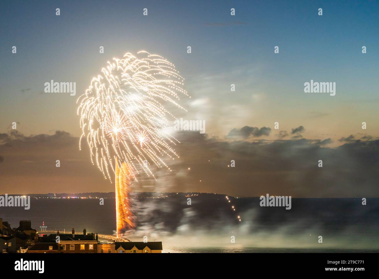 Fireworks bursting over the seafront and harbour at the Kent resort town of Herne Bay on a summer night. Isle of Sheppey in the background. Stock Photo