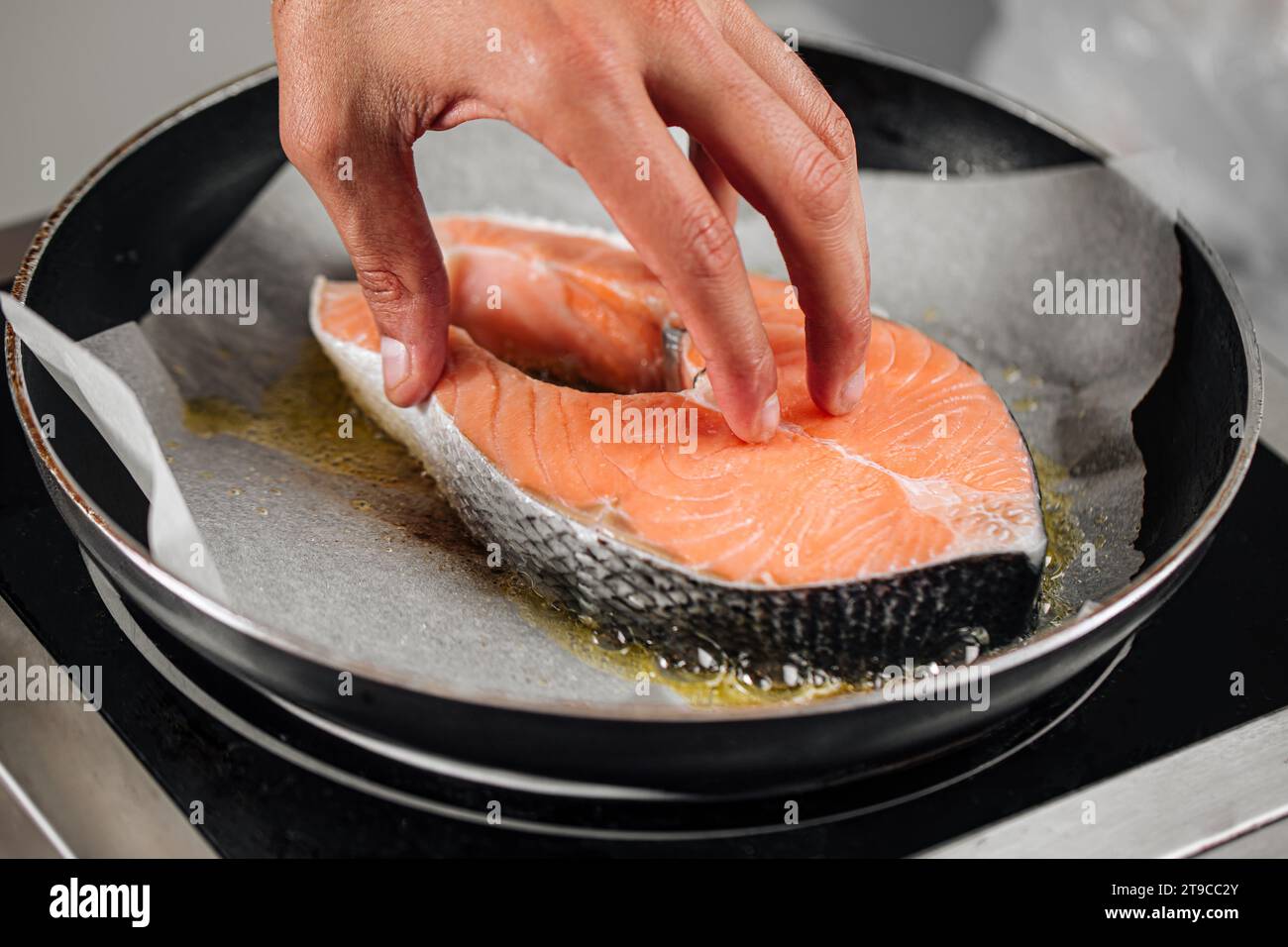 Man cooking salmon steak roasting on parchment Stock Photo
