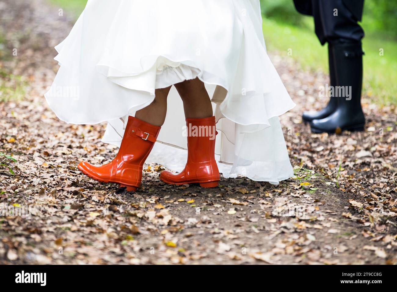 bride and groom low half crop of legs and wedding dress wearing orange and black wellies Stock Photo
