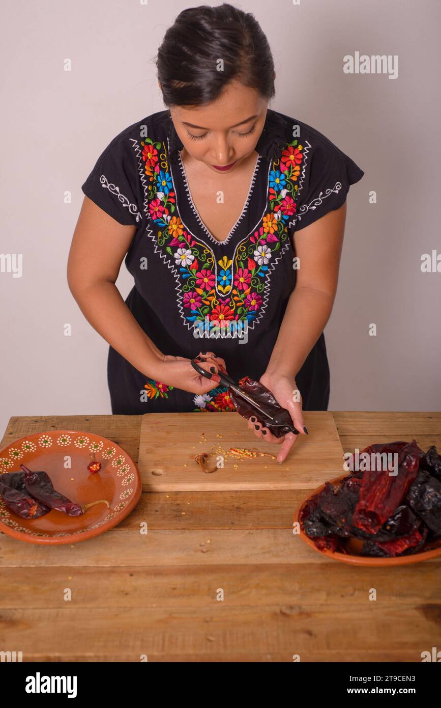 Woman opening ancho chili to remove the seeds. Ancho chili; condiment