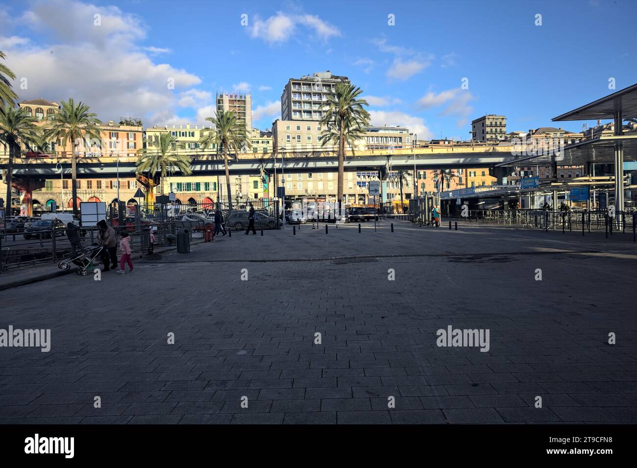 Genova, Italy - November 2023 - Waterfront with palms and people passing by and sitting on benches on a sunny day Stock Photo
