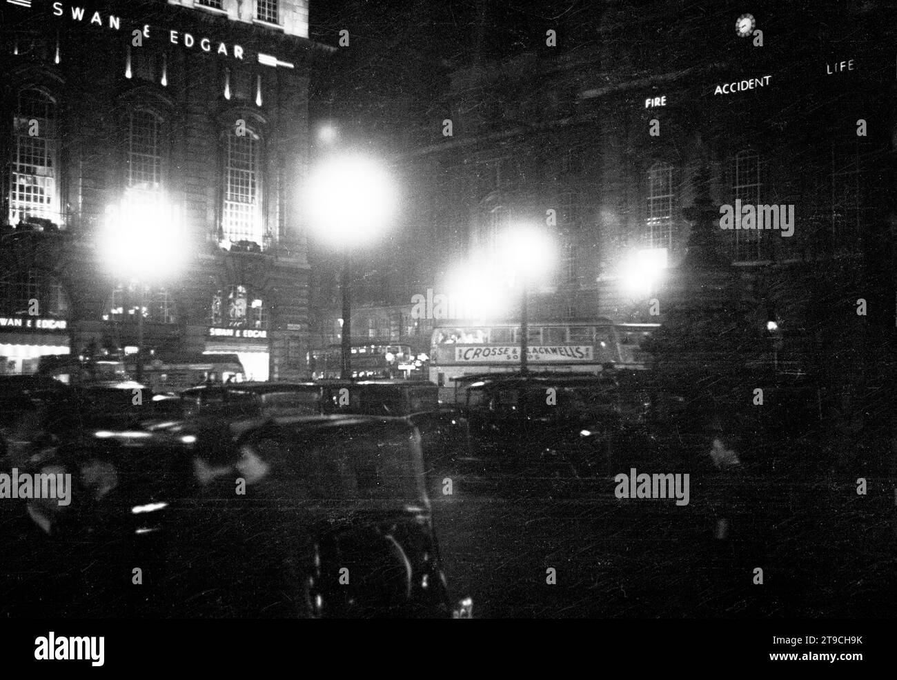 1940s, historical, nightime and heavy traffic congestion at the Piccadilly Circus road junction in this era. The famous department store of Swan & Edgar, a building which took up the entire of the corner of Piccadilly and Regent Street can be seen. Stock Photo