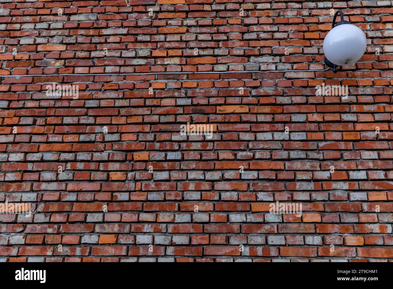Old red brick facade with a white suspended lamp, building in need of renovation Stock Photo