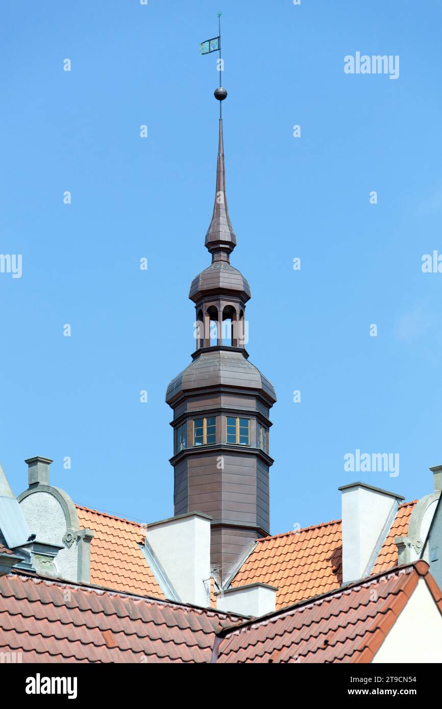 The abstract view of a narrow tall tower and colorful rooftops in Gdansk historic old town (Poland). Stock Photo