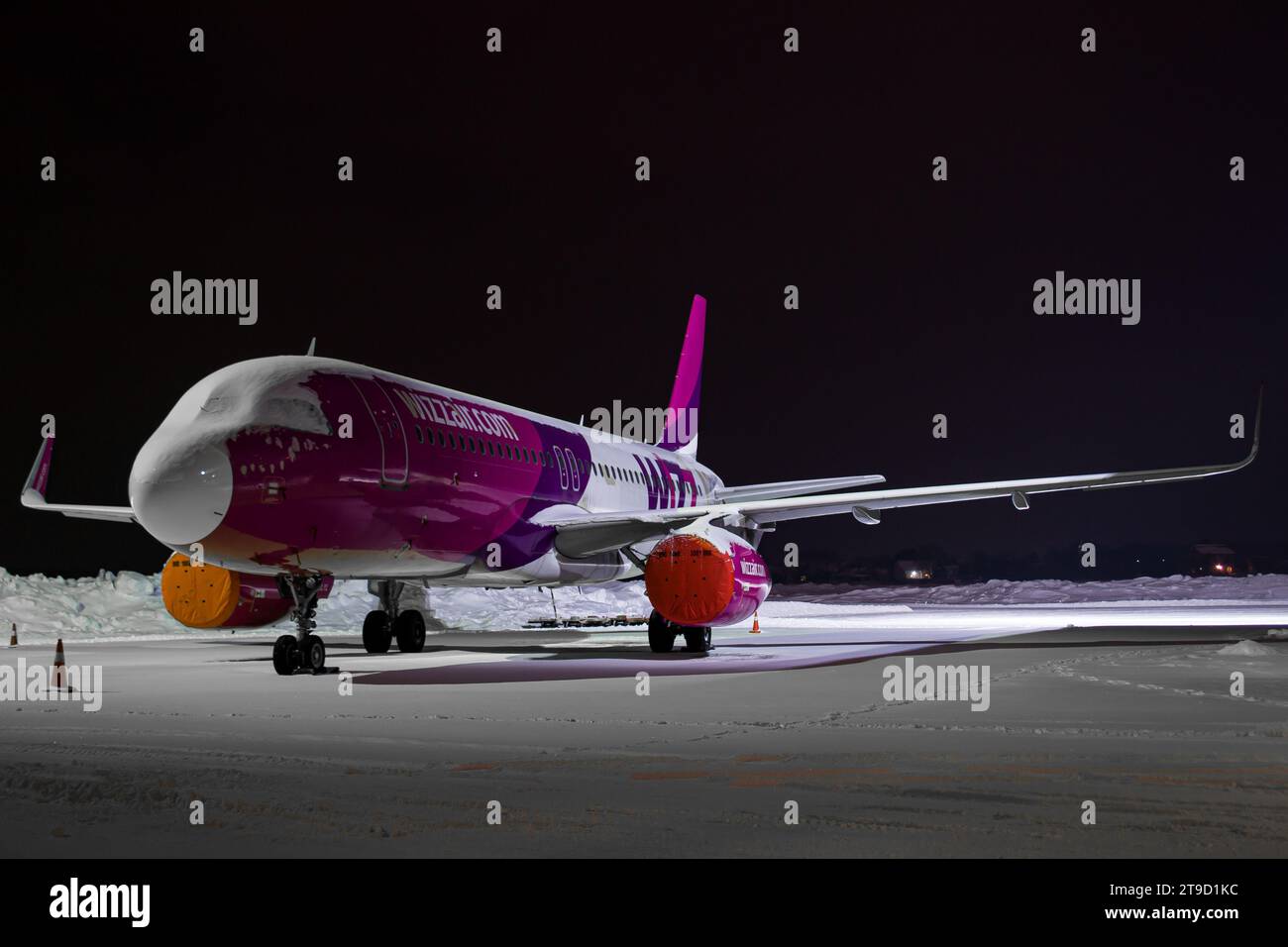 WizzAir Airbus A320 parked at the gate in Lviv, covered in snow, night photo Stock Photo