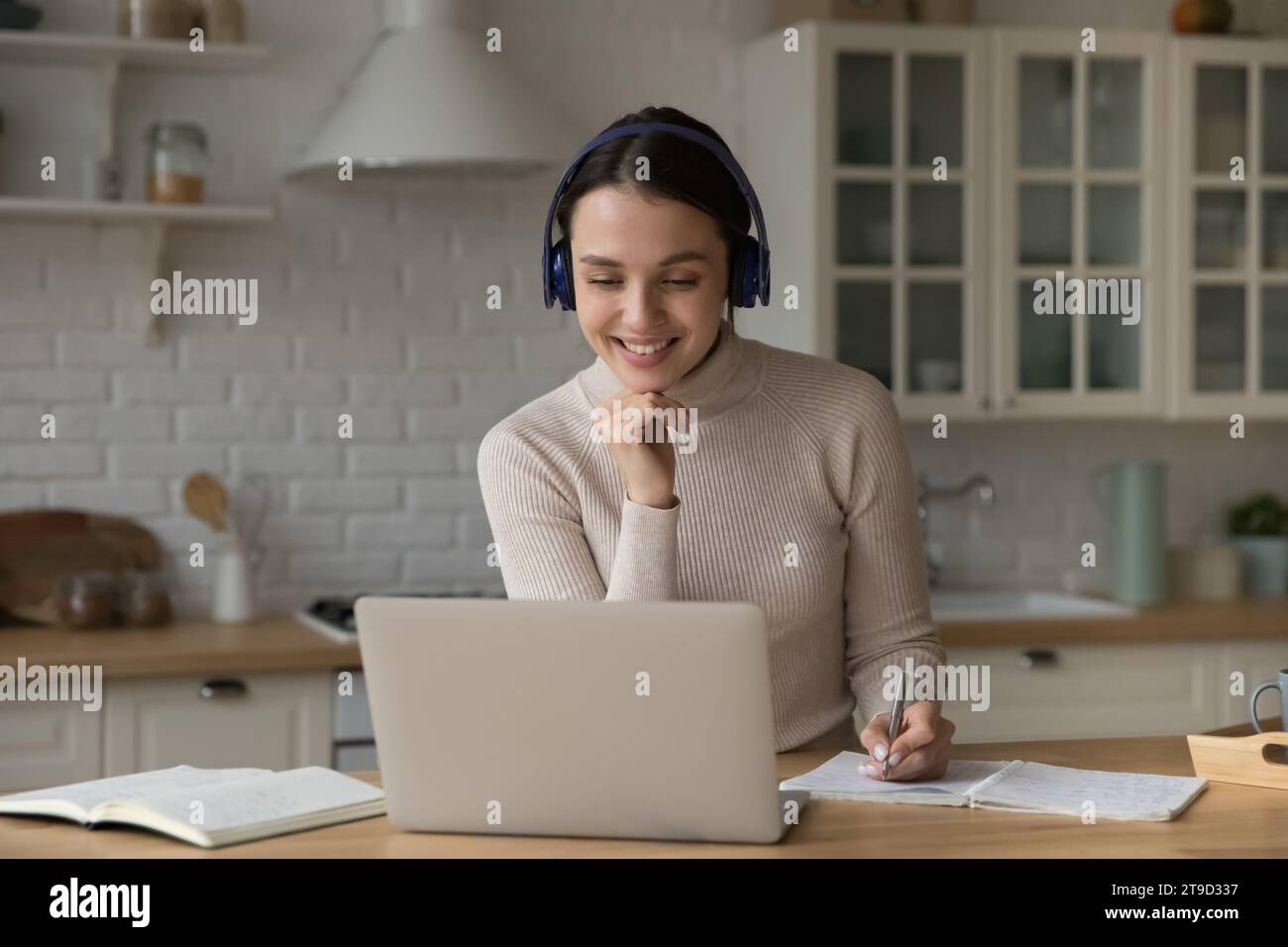 Student woman in headphones studying at home using laptop Stock Photo