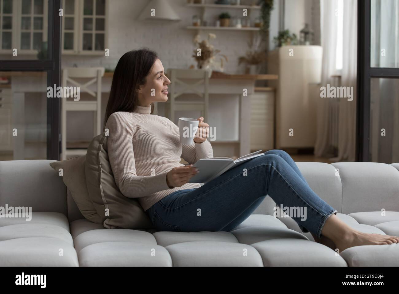 Peaceful woman relaxing on couch drink tea reading a book Stock Photo ...
