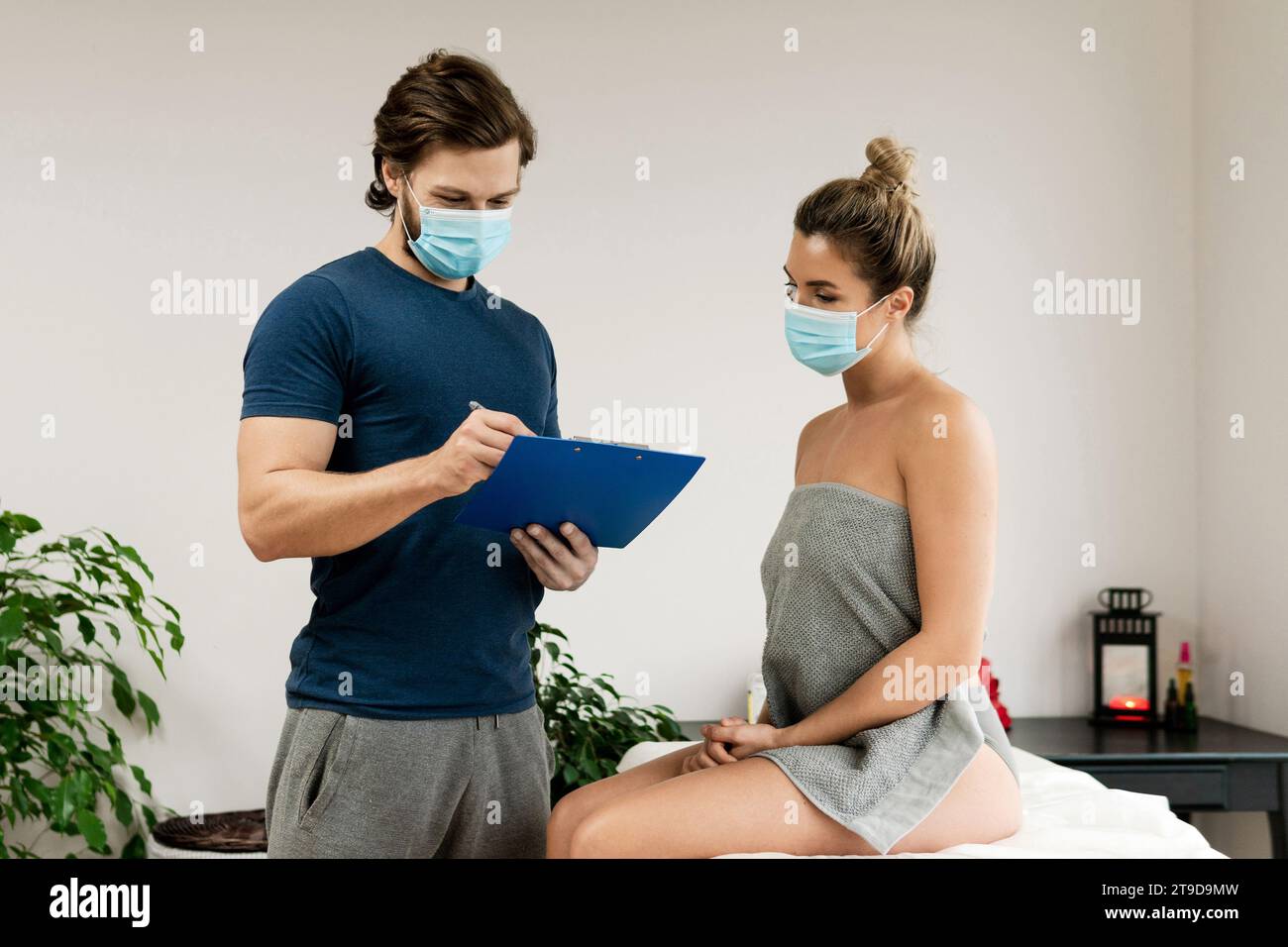 Man manual therapist wearing prevention mask is working with a woman ...