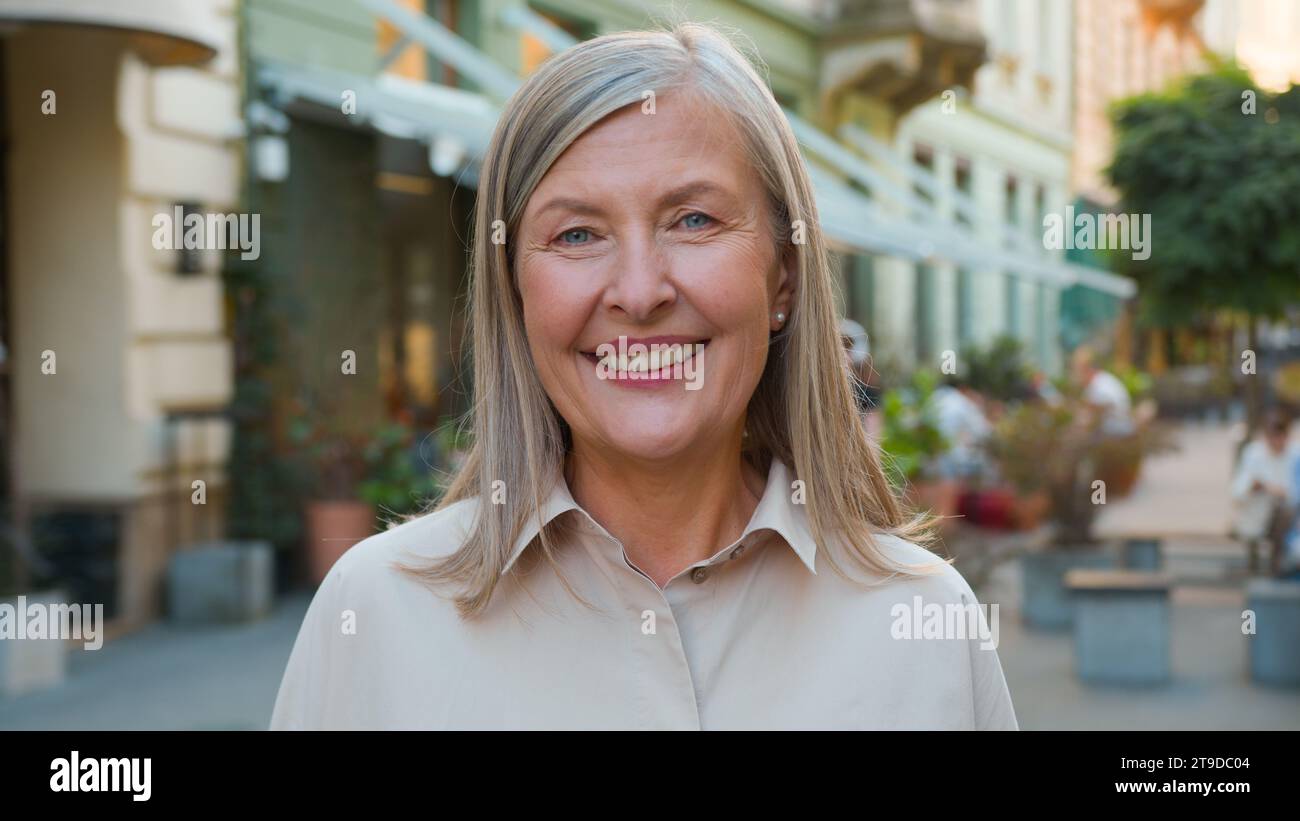 Close up portrait happy elderly mature gray-haired smiling laughing Caucasian European old retired businesswoman lady female tourist woman looking at Stock Photo