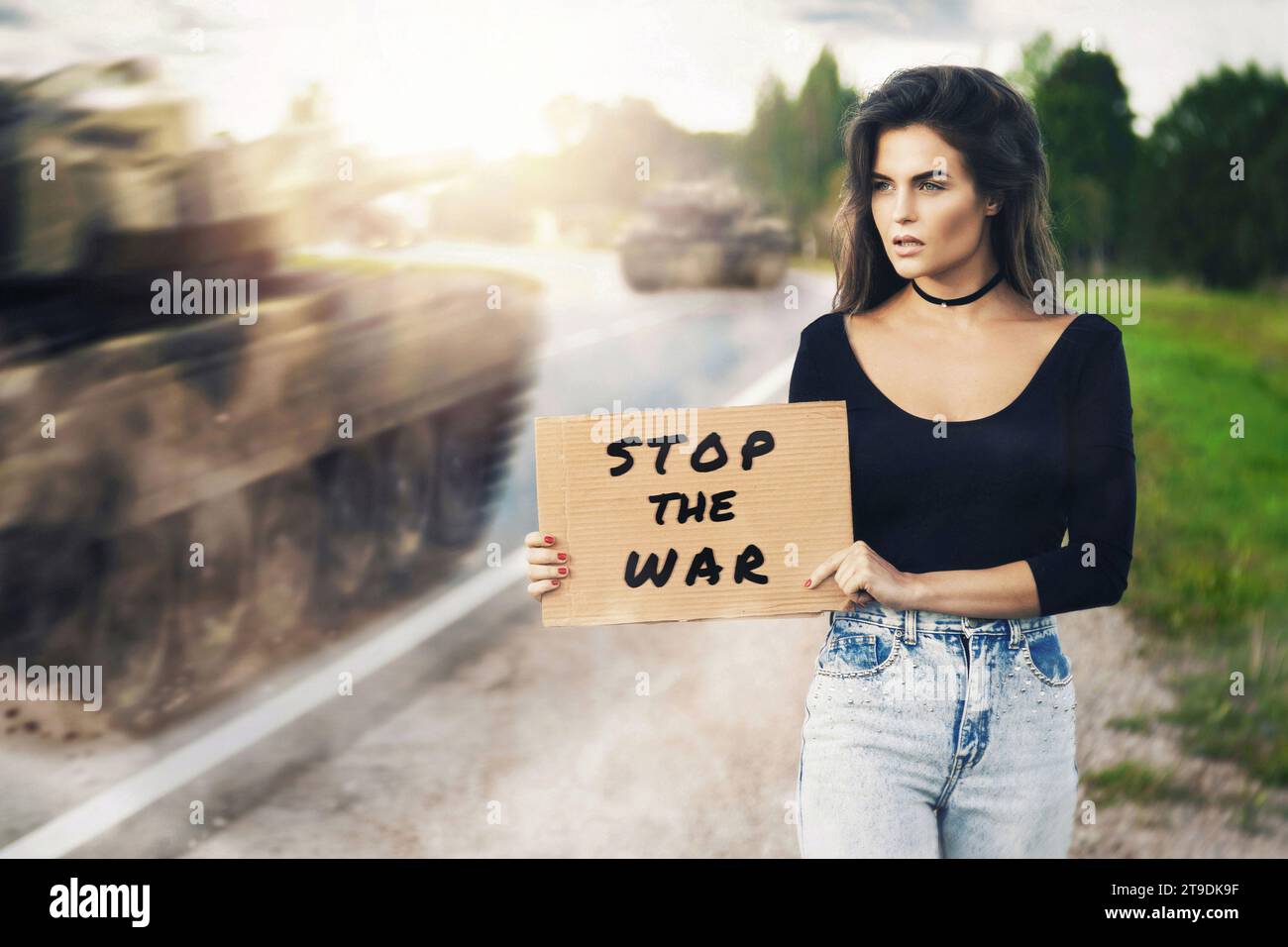 Young woman activist with banner STOP THE WAR near road with moving ...