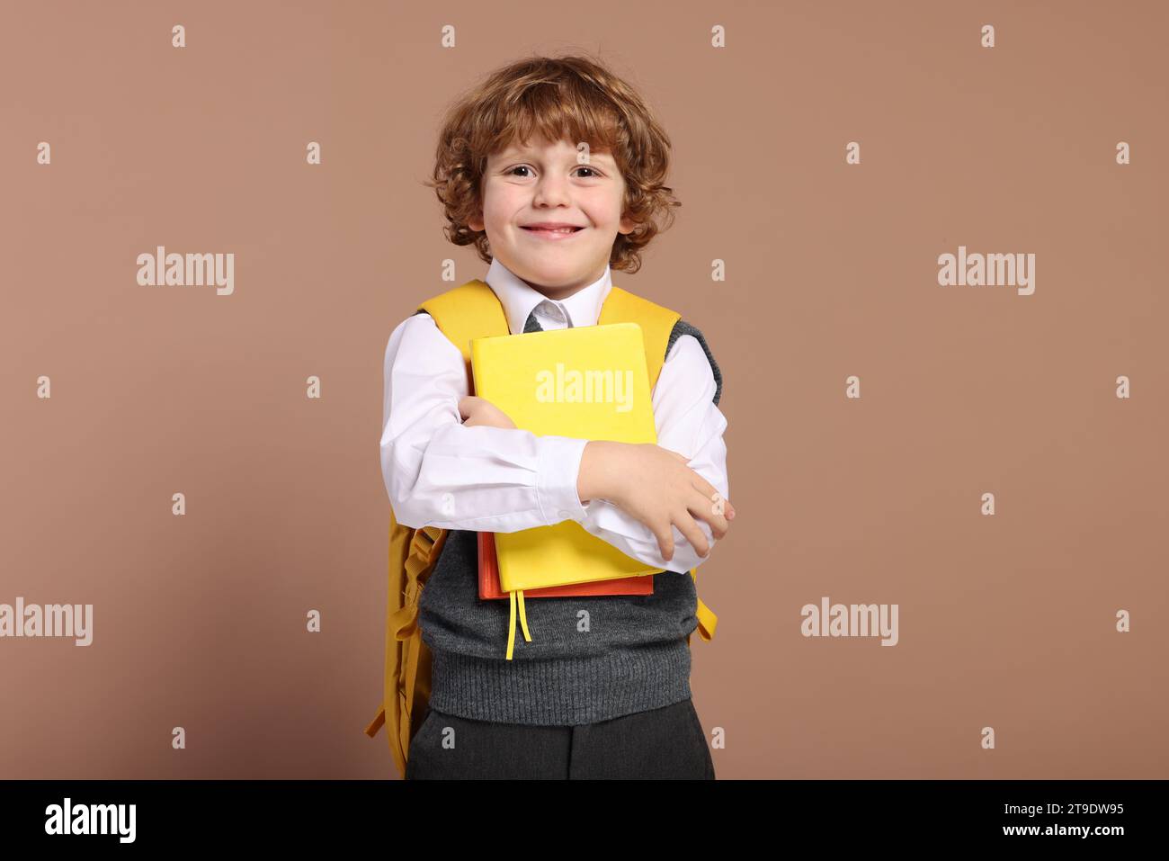 Happy schoolboy with backpack and books on brown background Stock Photo ...