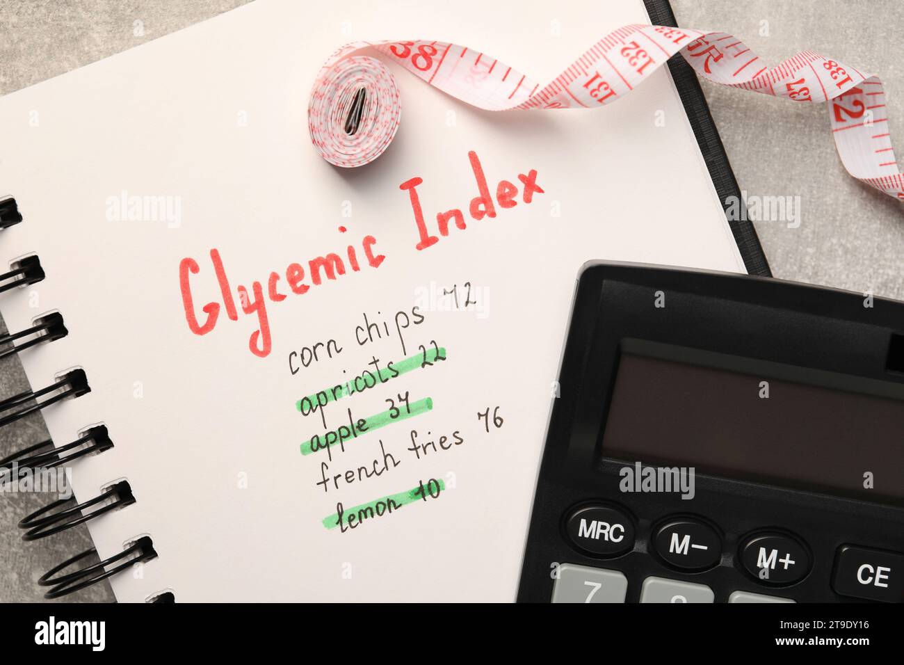 Glycemic Index. Notebook with information, measuring tape and calculator on light grey table, flat lay Stock Photo