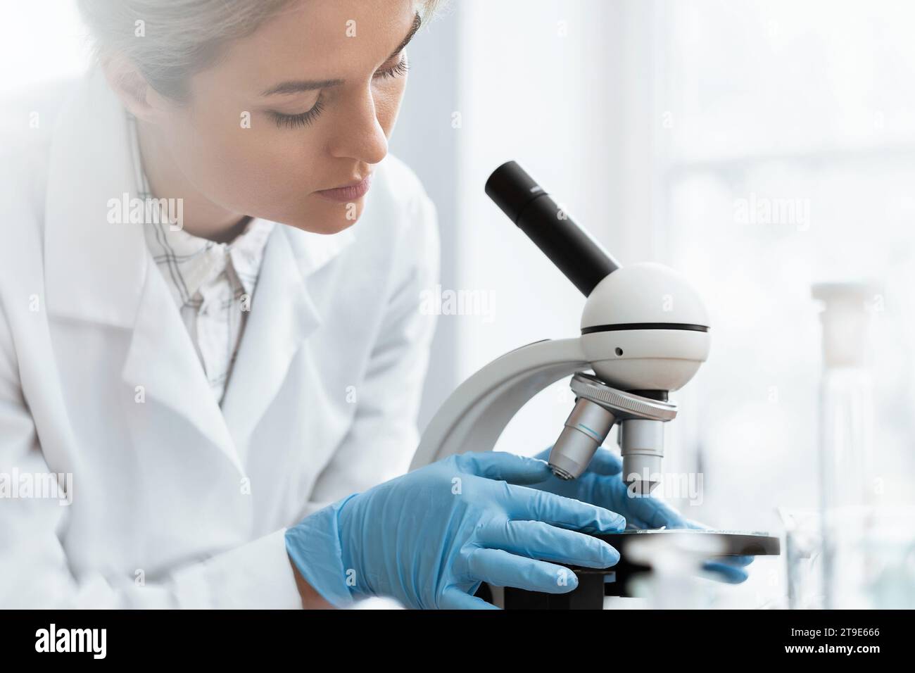 Woman student is using microscope in a laboratory during science research work Stock Photo