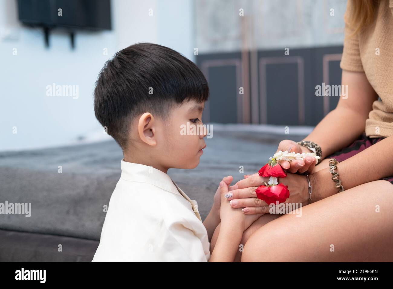 Little asian boy Giving a jasmine garland to mother On Thailand's National Mother's Day Stock Photo