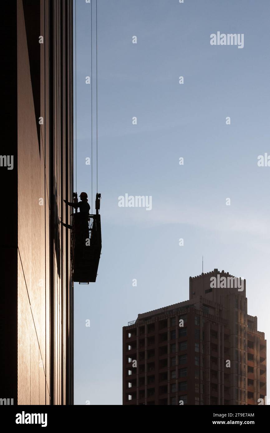 Window cleaners and building maintenance engineers in a gondola on the side of Mynds Tower in a Shinjuku, Tokyo, Japan Stock Photo