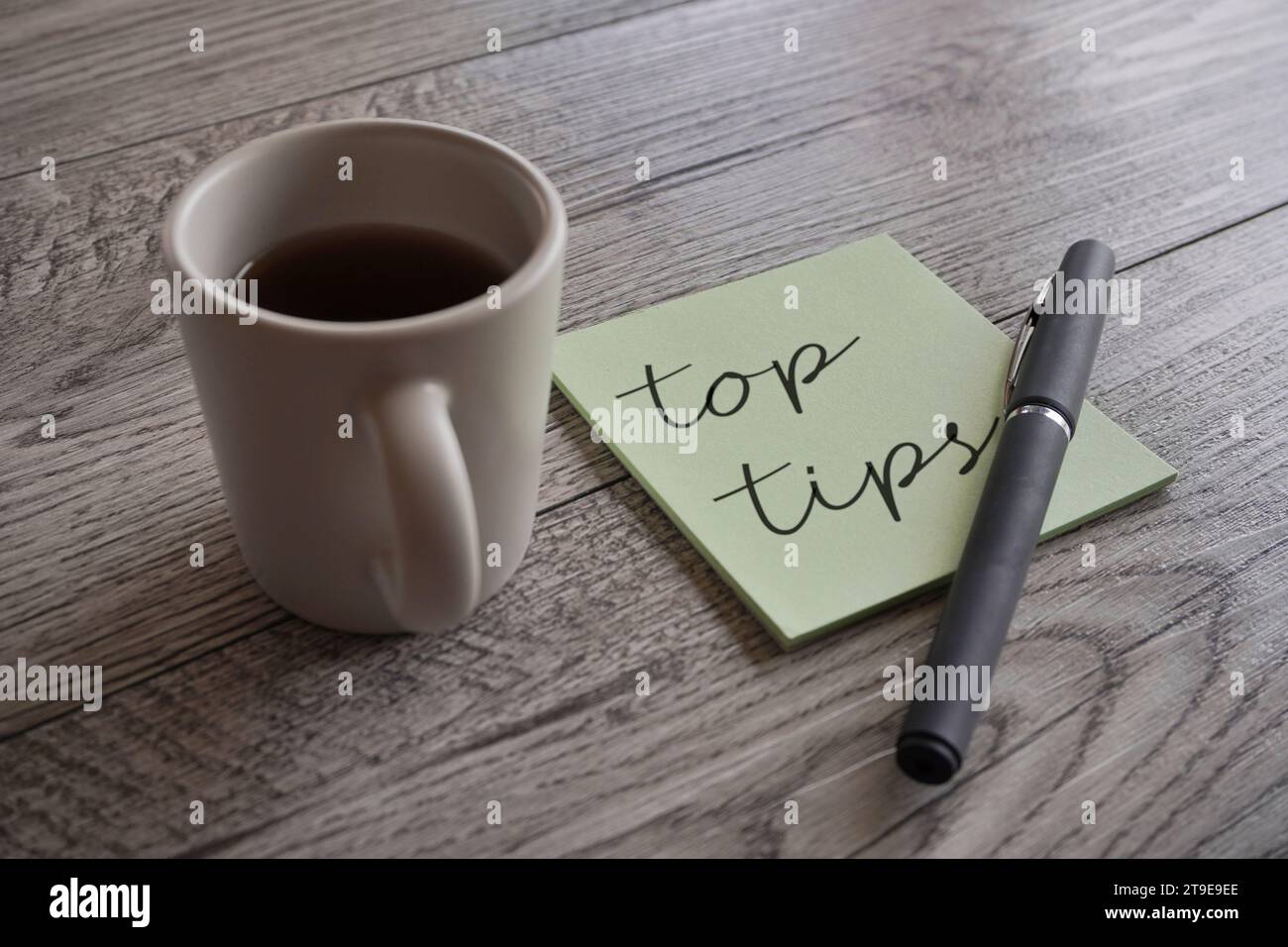 Closeup image of cup of coffee, pen and sticky note with text TOP TIPS. Stock Photo