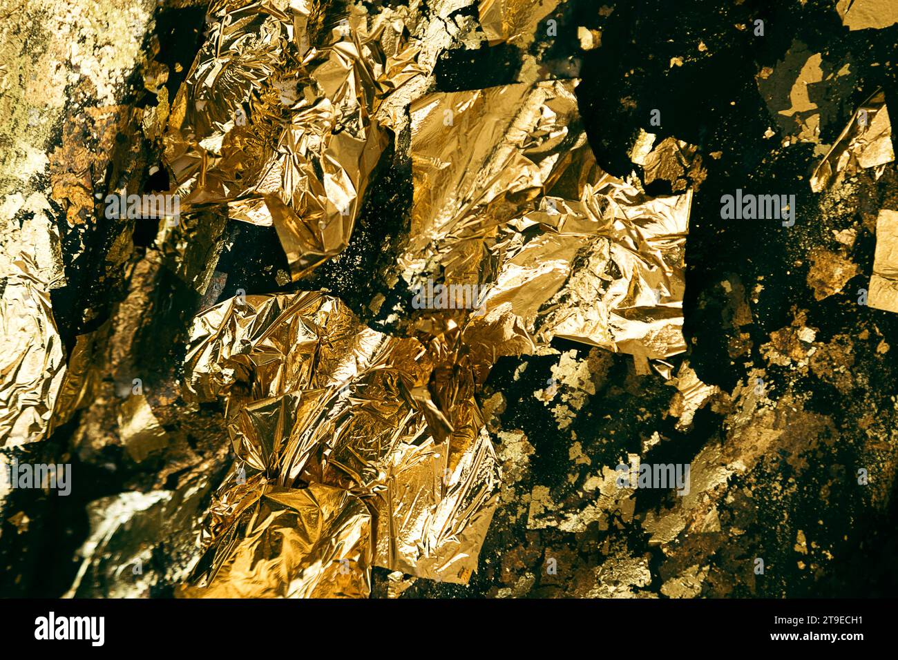 Abstract closeup shot of a uneven surface covered with exfoliated crumpled gold foil. Stock Photo