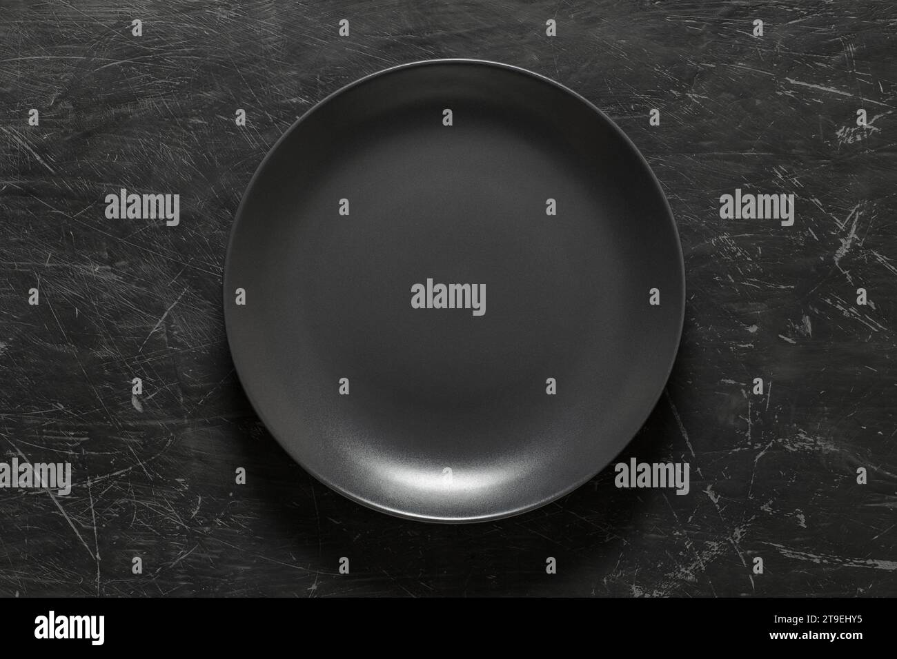 Grey round plate on dark background, top view. Stock Photo