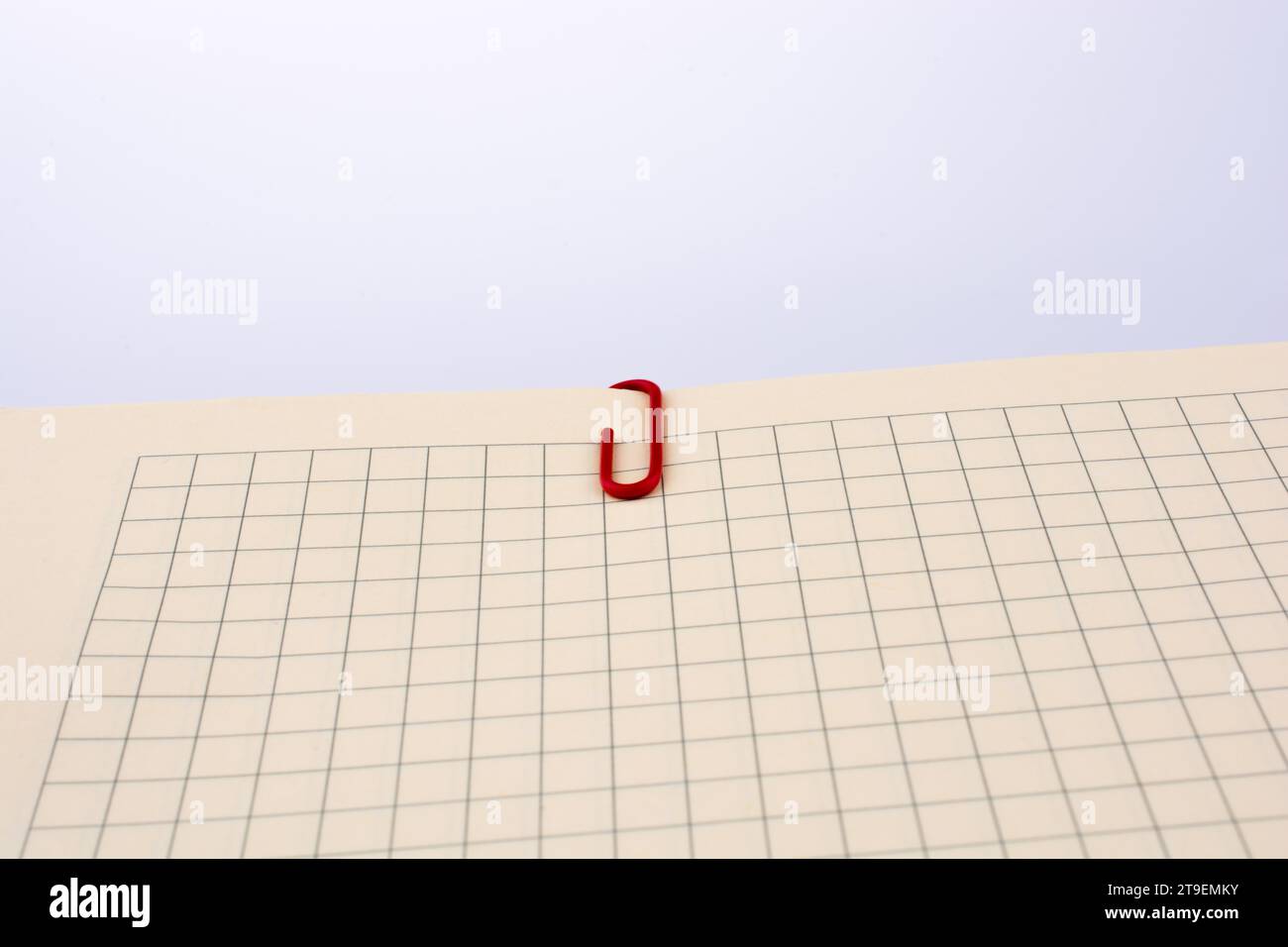 Colored paper clip on a checked notebook page Stock Photo