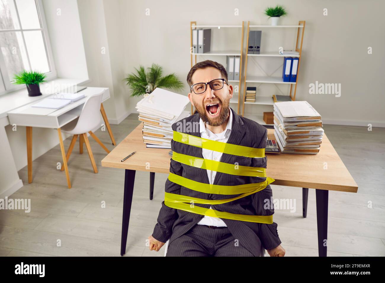 Tired man, stuck at work in office like slave, sitting tied to chair and screaming for help