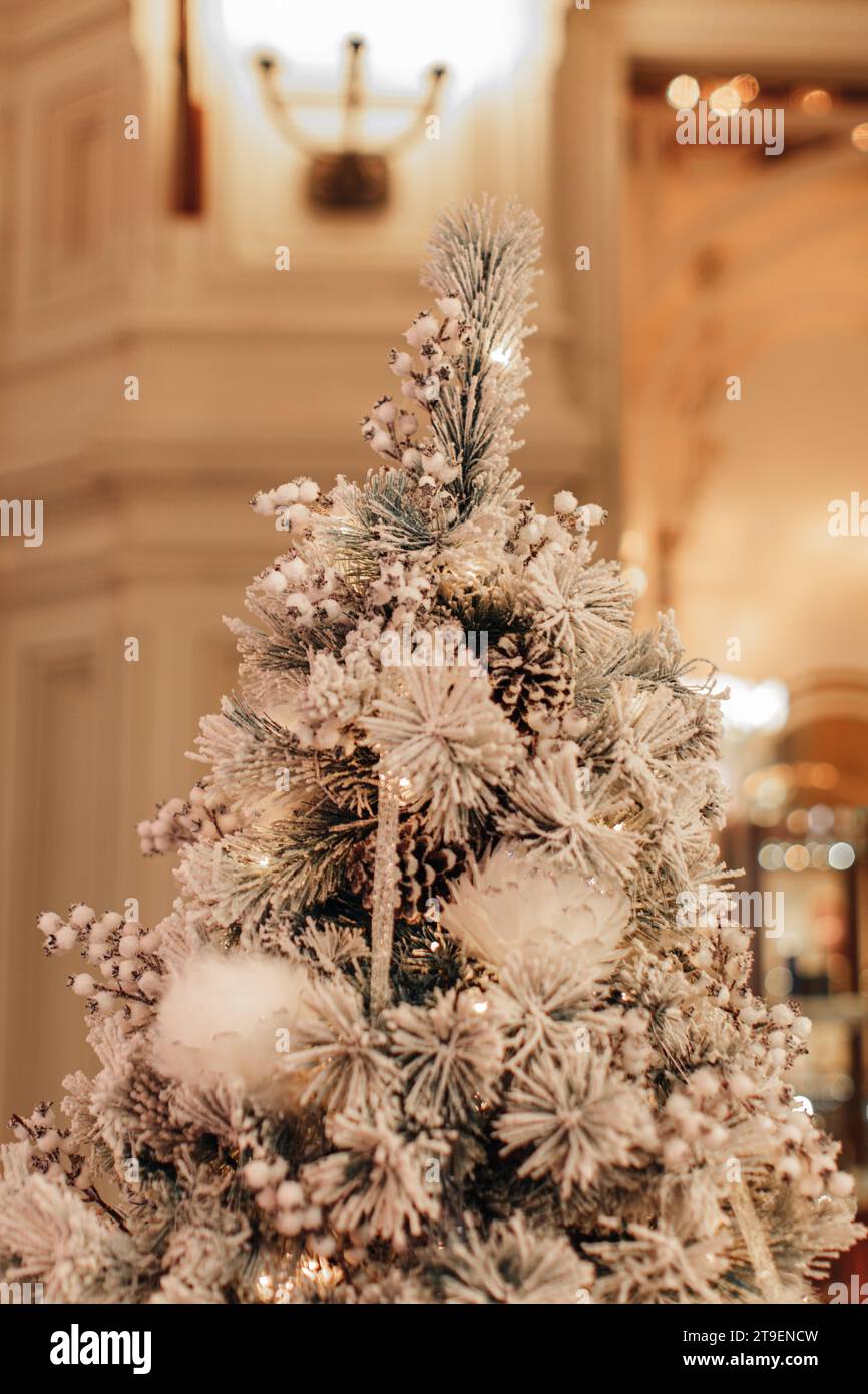 A traditional snow covered Christmas tree, decorated with snowflakes and forest cones. Festive details in the interior Stock Photo