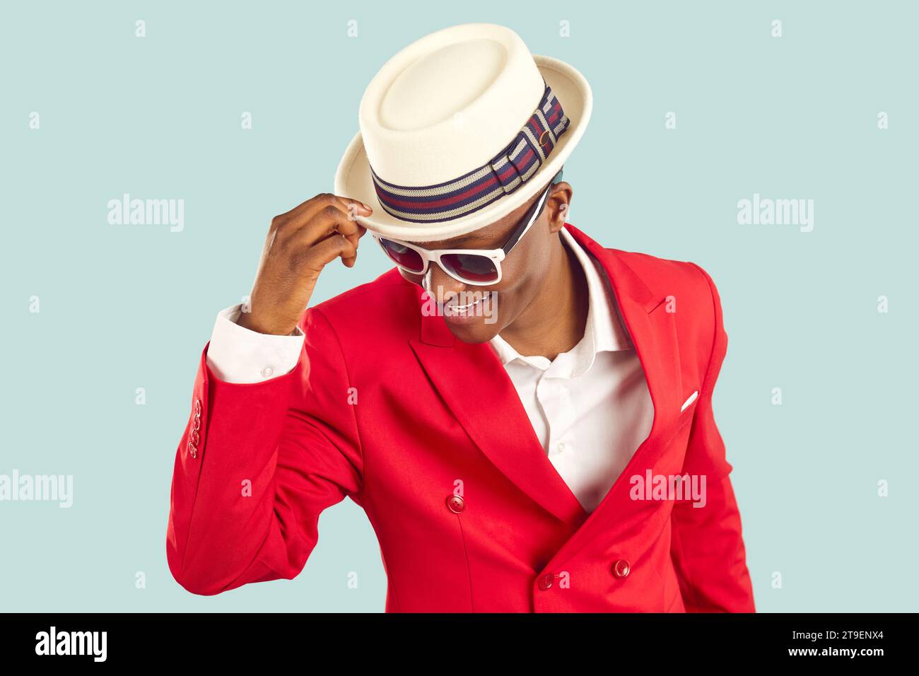 Young trendy African American man in stylish sunglasses and bright red jacket stands in studio Stock Photo