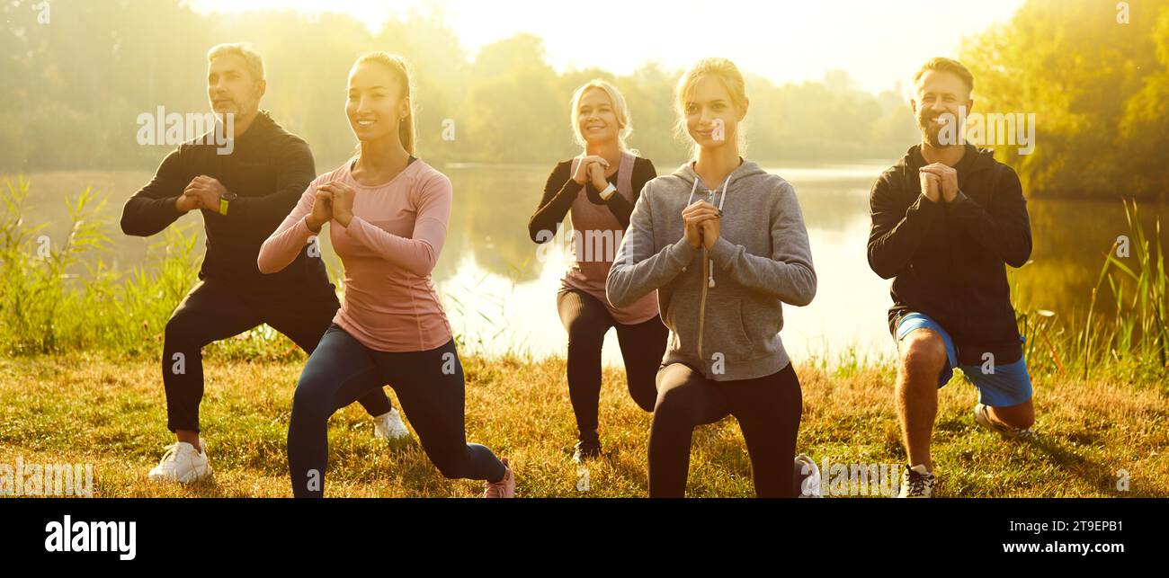 Group of fit and active people doing stretching exercising in nature. Outdoors fitness concept. Stock Photo