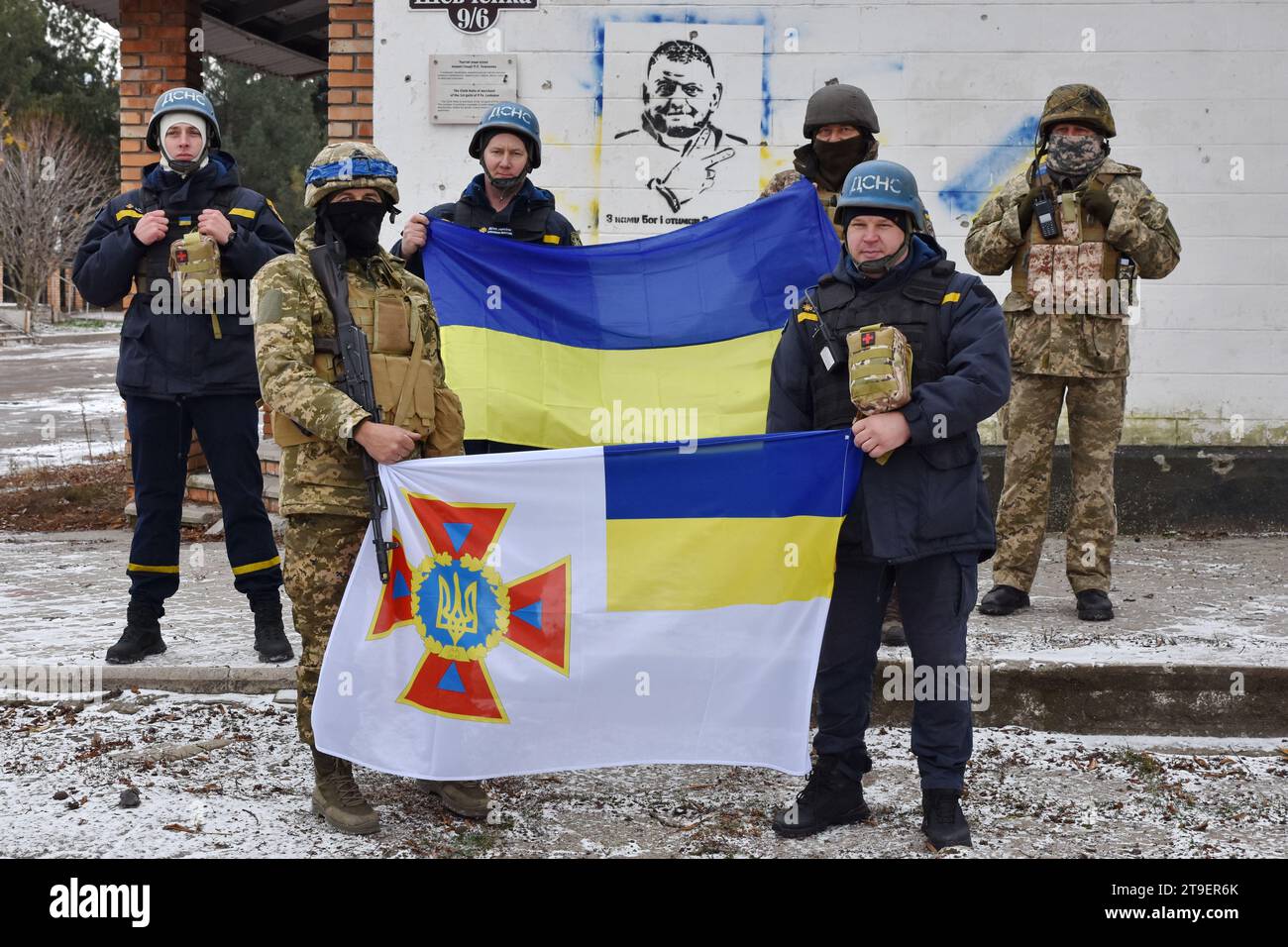 Huliaipole, Ukraine. 23rd Nov, 2023. Ukrainian army soldiers and firefighters hold a Ukrainian flag and a Ukrainian State Emergency Service flag in front of the graffiti depicting General Valery Zaluzhny, head of Ukraine's armed forces in the center of Huliaipole. Ukraine confirmed this week that it had managed to maintain its positions along the left bank of the Dnipro River, which had been completely under Russian control. These successes suggest that a major Ukrainian counteroffensive, aimed at reclaiming Crimea, could soon be under way. Credit: SOPA Images Limited/Alamy Live News Stock Photo