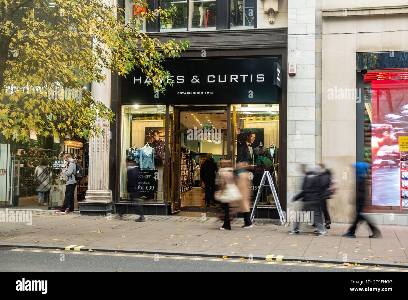 LONDON- NOVEMBER 23, 2023: Hawes and Curtis, British fashion retail shop and motion blurred shoppers on Oxford Street, landmark retail destination Stock Photo