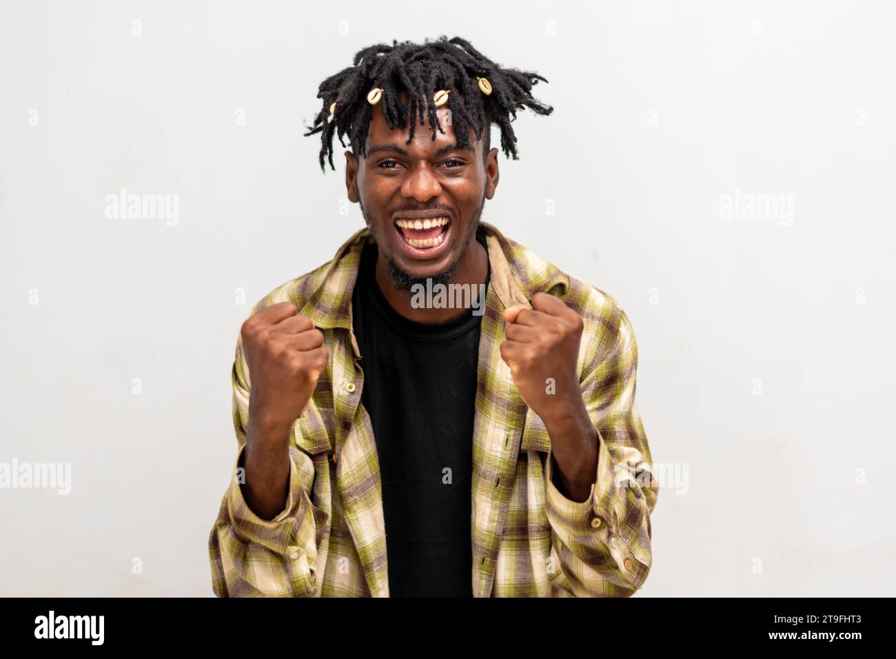 excited young black guy on dreadlocks raising fist up on white background, celebrating success. Happy african millennial man sharing positive emotions Stock Photo
