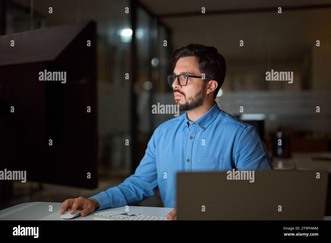 Busy young business man programmer using computer working late in office. Stock Photo