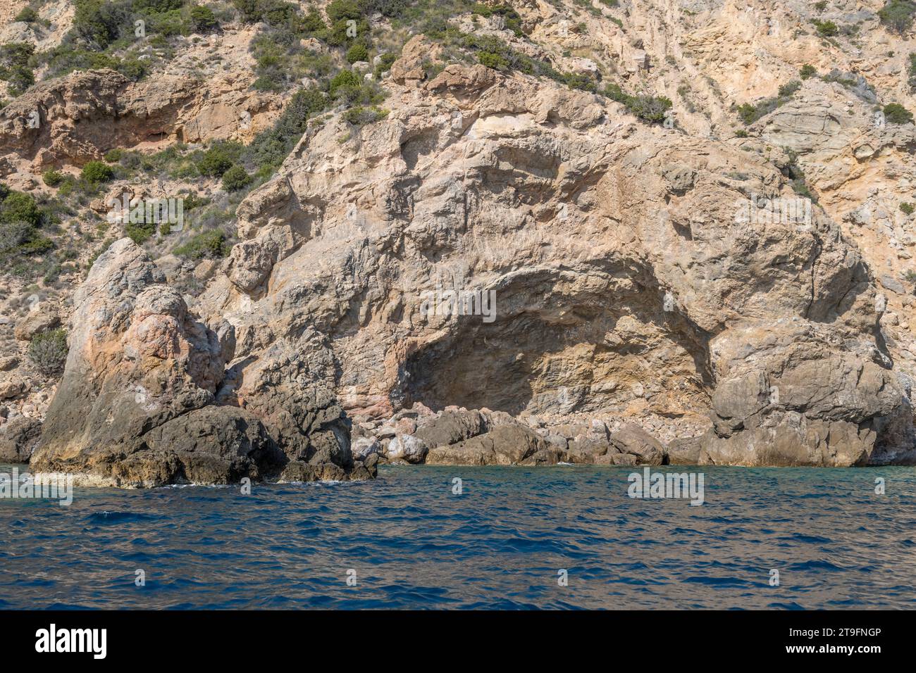 detail of layered igneous rocks hole in steep layered cliffs of Uomo ...