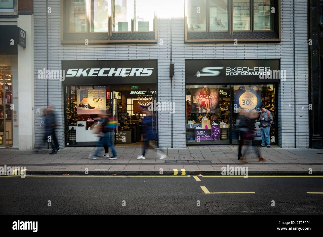 LONDON- NOVEMBER 23, 2023: Skechers footwear shop and motion blurred shoppers on Oxford Street, landmark retail destination Stock Photo