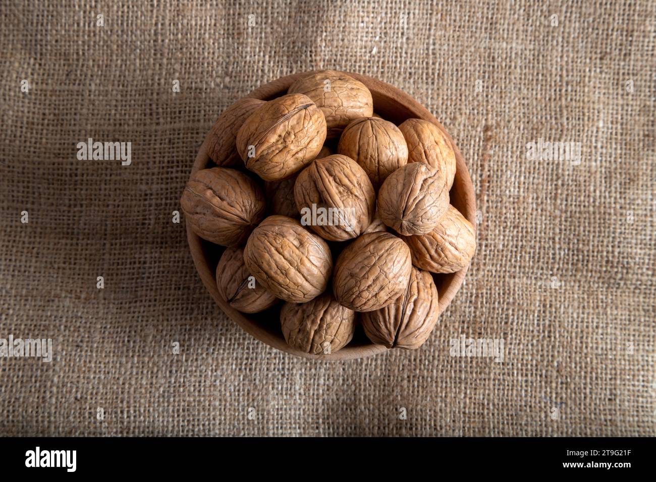 Bowl full of shelled walnuts on burlap sack,top view Stock Photo