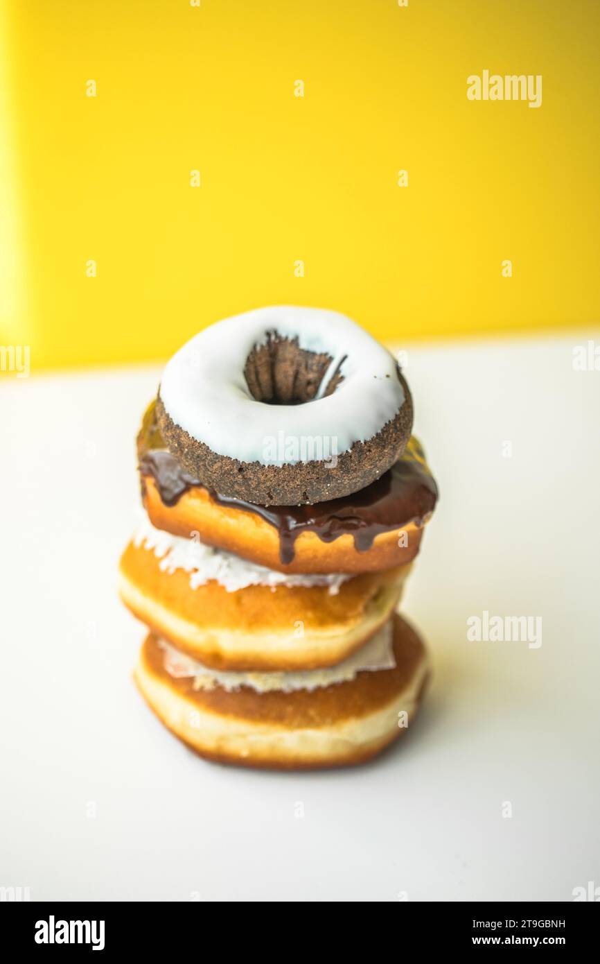 Sweet donuts of different bright colors lie in a large pile on a colored background Stock Photo